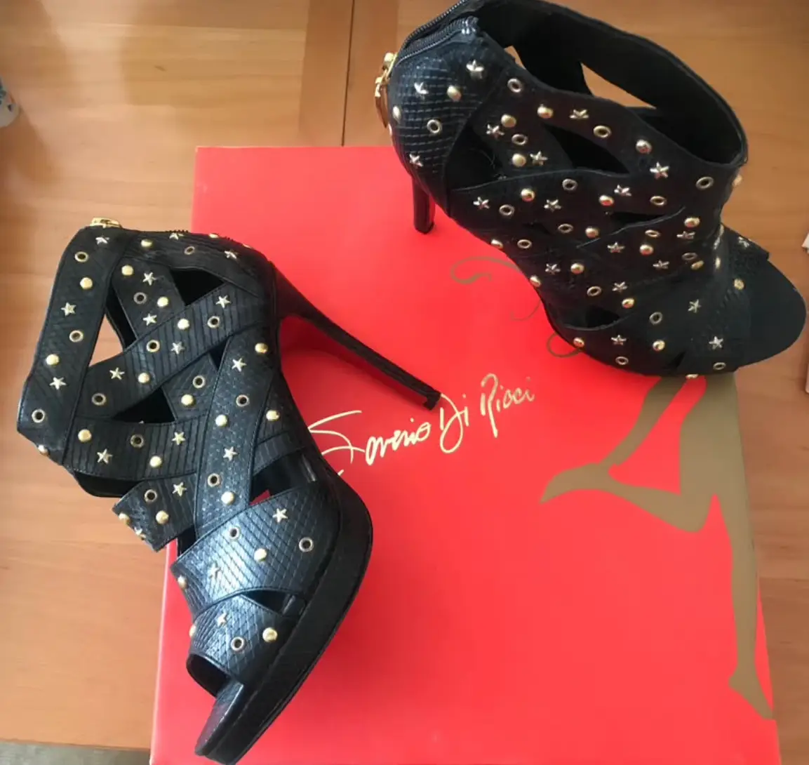 Sandalias de taco alto negras con detalles dorados y diseño calado, con cierre parte trasera.  Ideales para fiestas y eventos especiales.