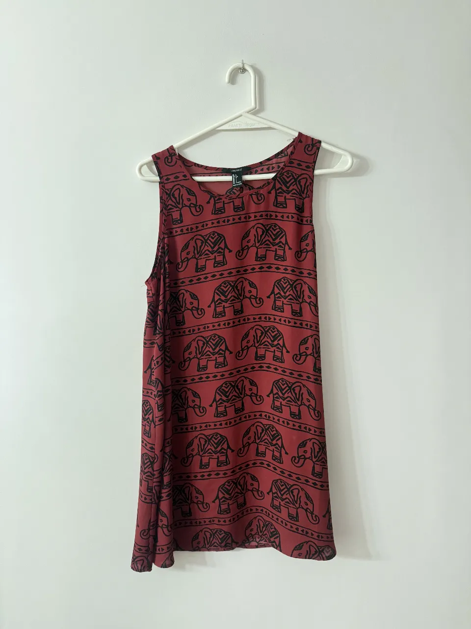 Vestido corto de mujer, sin mangas, con estampado de elefantes en color negro sobre fondo rojo. Ideal para un look casual y fresco.