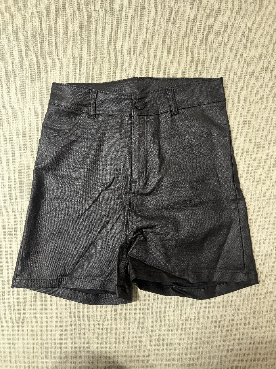 Short de mujer negro, tiro alto, con bolsillos delanteros y traseros. Confeccionado en material símil cuero. Ideal para un look moderno y audaz.