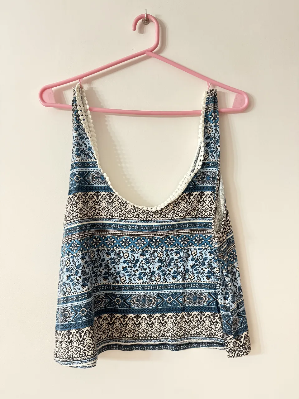 Remera con estampado floral en tonos azules y blancos, ideal para un look bohemio y fresco. Detalles de encaje en el borde superior.
