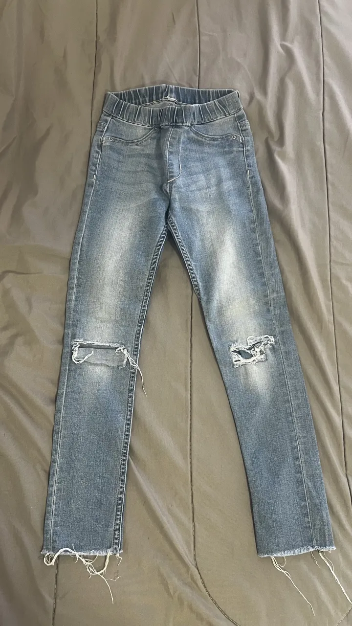 Jeans de denim con roturas en las rodillas y detalles deshilachados en los bajos. Cintura elastizada.