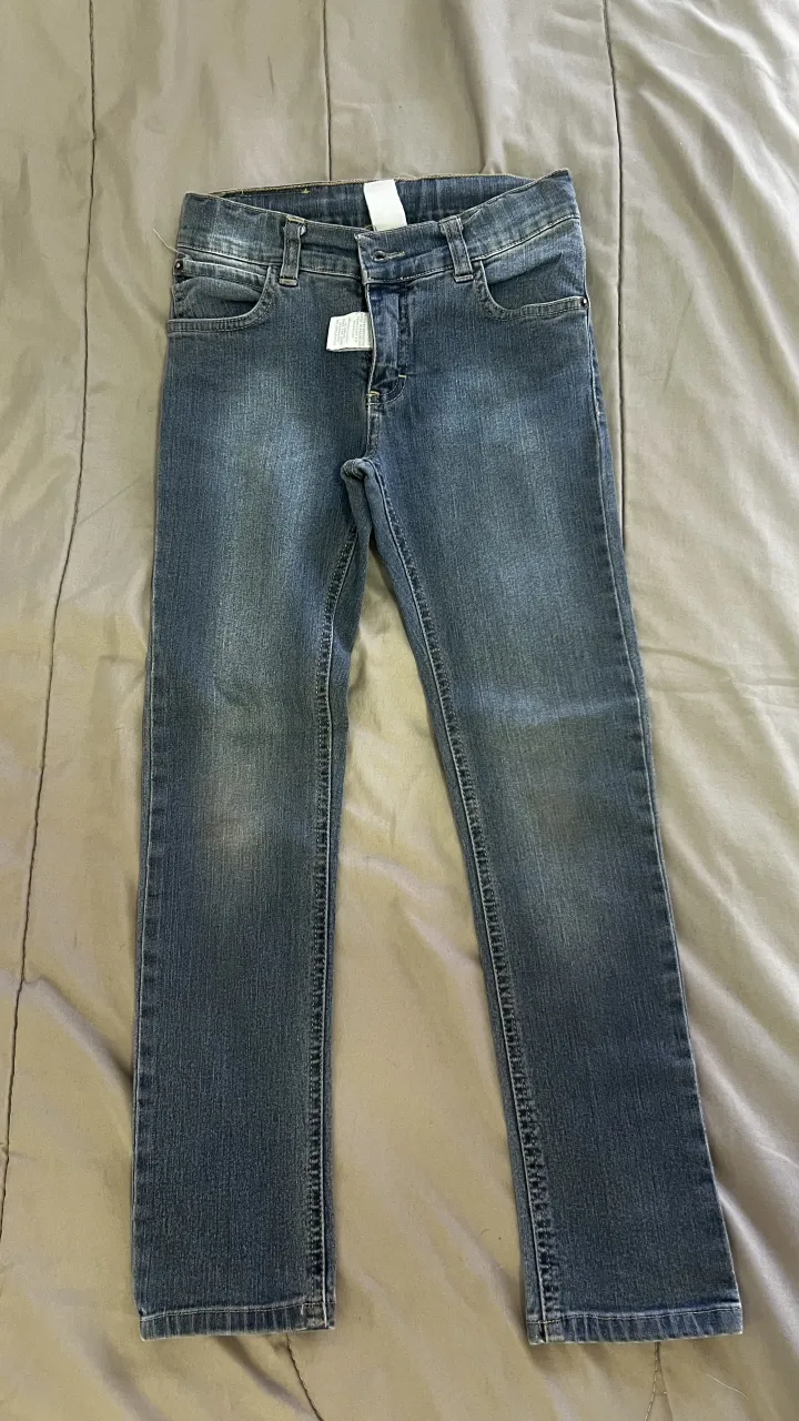 Jeans de algodón azul con desgaste sutil. Cierre y botón.