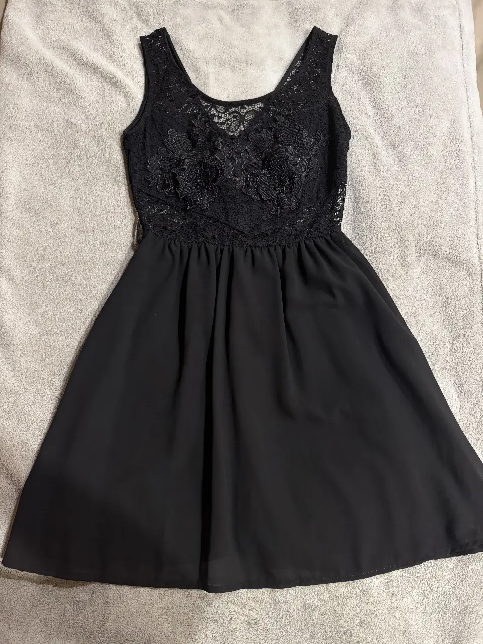 Vestido negro corto con corpiño de encaje floral y falda fluida. Ideal para fiestas y eventos especiales.