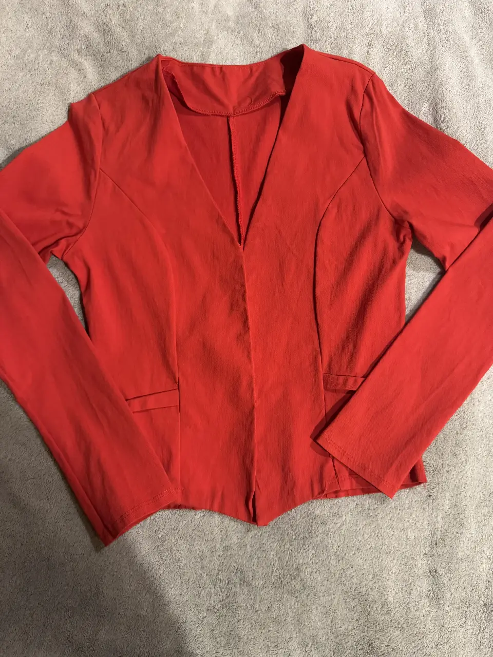 Blazer rojo entallado con cuello en V y bolsillos delanteros. Ideal para un look elegante y moderno.