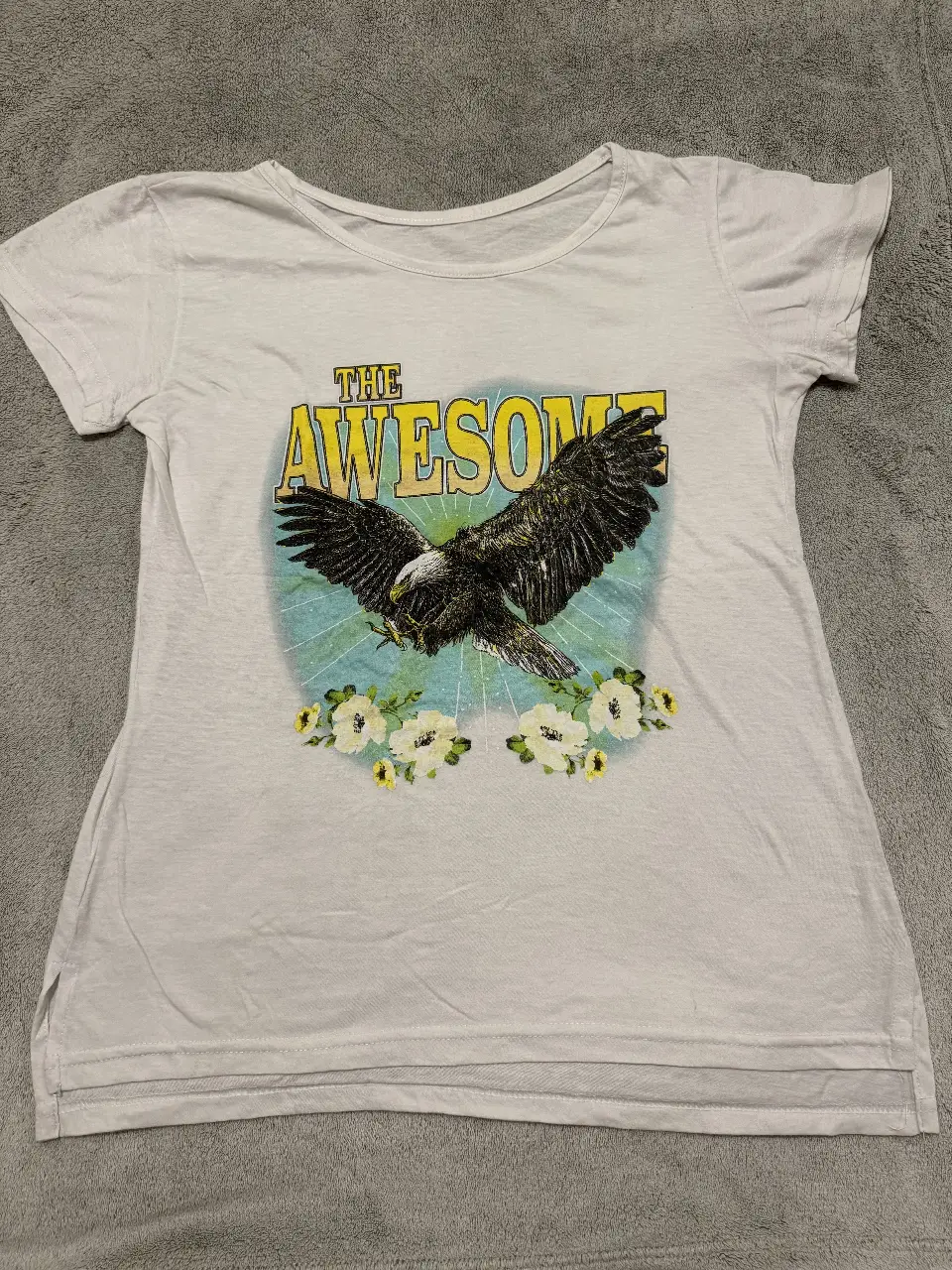 Remera blanca de algodón con estampado "The Awesome" con un águila y flores. Ideal para un look casual y con onda.