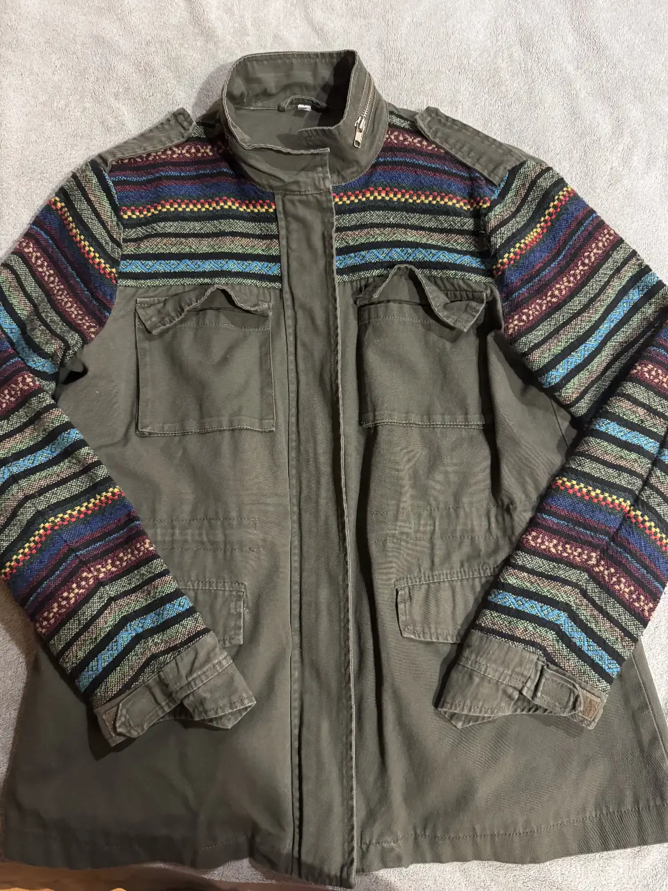 Campera estilo bomber de hombre, color verde militar con mangas estampadas en tonos vibrantes. Ideal para un look casual y con onda.