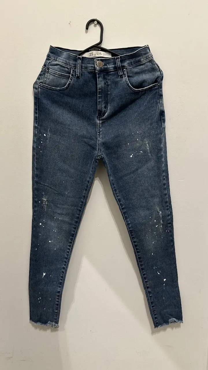 Jeans de mujer tiro alto, con detalles de salpicaduras blancas. Corte recto y largo por encima del tobillo. Ideal para un look casual y moderno.