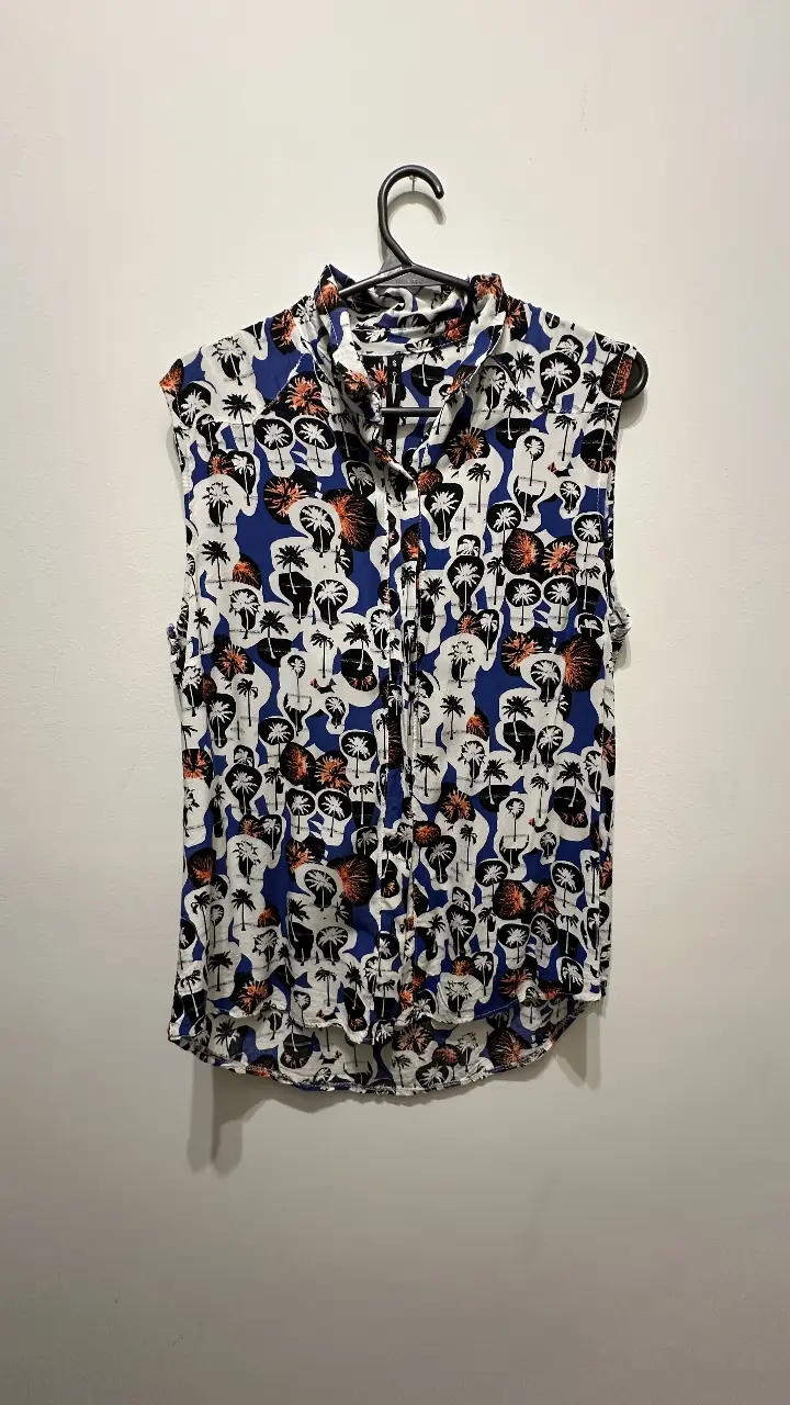 Camisa sin mangas con estampado de palmeras en blanco y negro sobre fondo azul. Ideal para un look fresco y casual.