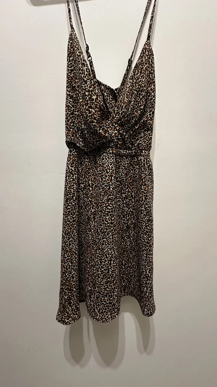 Vestido mini de mujer con estampado de leopardo. Tiene tirantes finos y un diseño cruzado en el busto. La cintura es elastizada. Ideal para una salida casual o de fiesta.
