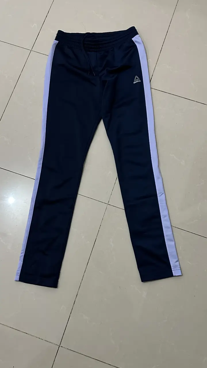 Pantalón deportivo de mujer, color azul marino con detalles en blanco. Con el logo de Reebok. Talle XS.
