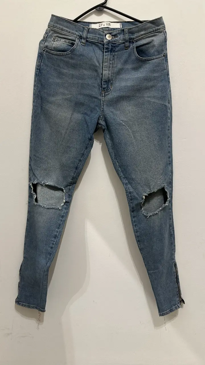 Jeans de mujer, tiro alto, con roturas en las rodillas y cierre en los tobillos. Talle 27.