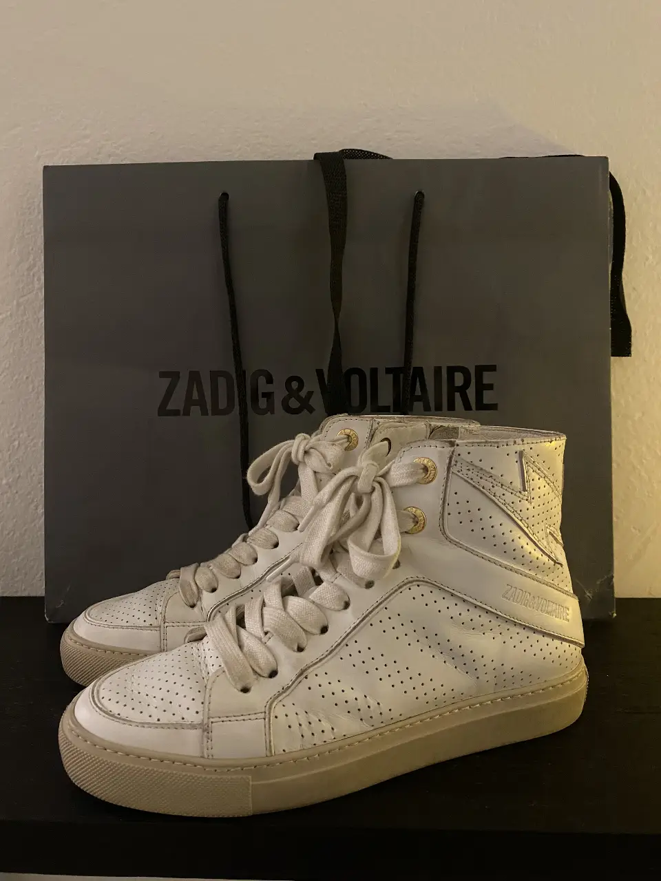 Zapatillas Zadig & Voltaire de cuero blancas, estilo botita con detalles perforados y cierre lateral. Ideales para un look casual y moderno.