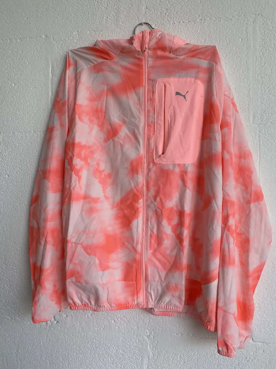 Campera rompevientos Puma con capucha, con estampado tie dye en tonos rosa y blanco. Posee bolsillo con cierre y logo de la marca. Ideal para running y actividades al aire libre.