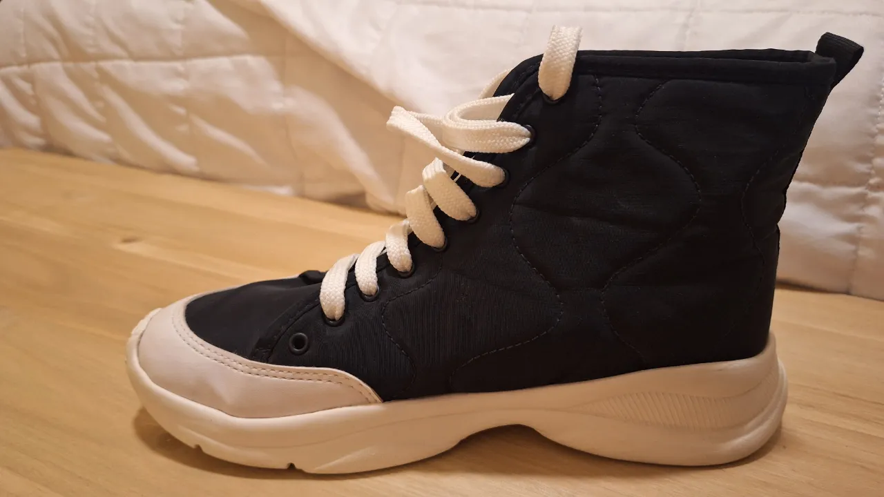 Zapatillas negras con detalles blancos, ideales para un look casual y moderno. Confortables y con suela resistente, perfectas para el día a día.