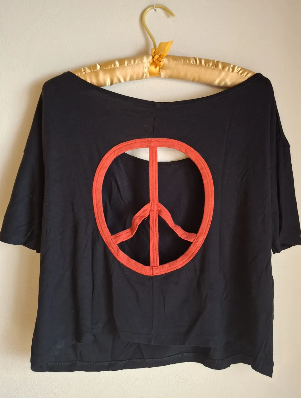 Remera negra crop con un llamativo aplique de símbolo de la paz en rojo en la espalda. Diseño moderno y canchero, ideal para un look relajado y con onda.