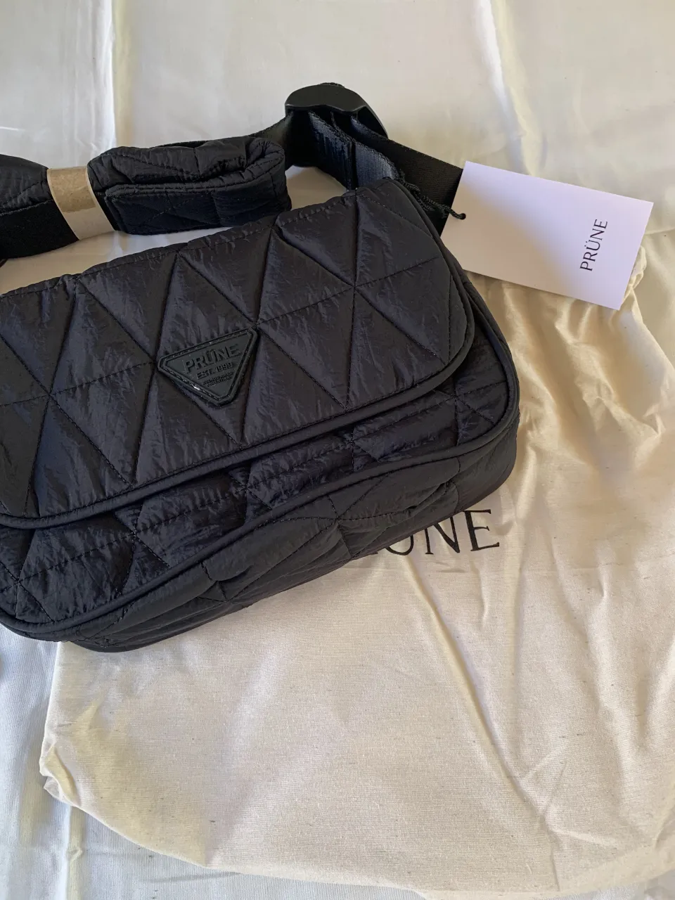 Bolso negro acolchado con diseño de rombos. Tiene correa ajustable y es perfecto para el día a día o para llevar tus esenciales con estilo.