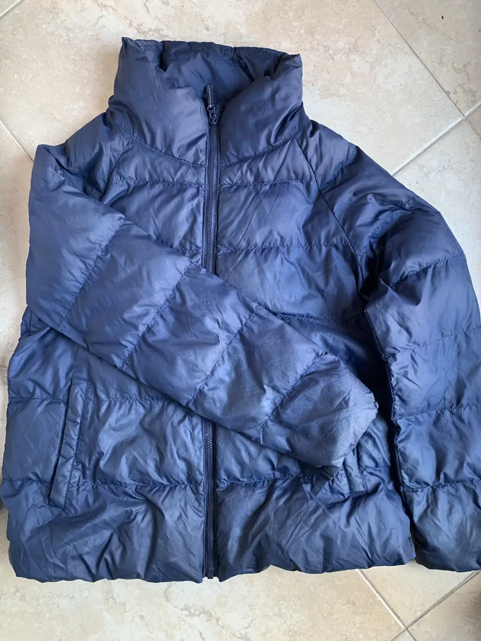 Campera de pluma azul marino de la marca Uniqlo, ideal para el invierno. Posee cierre frontal, cuello alto y bolsillos laterales. Perfecta para mantenerte abrigado con estilo. Talle como para 11/12 años 