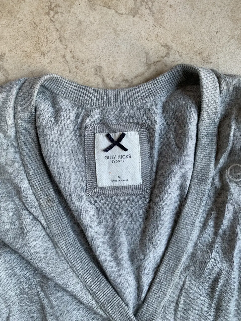 Cardigan gris de la marca Gilly Hicks Sydney, con cuello en V y botones. Ideal para un look casual y cómodo.