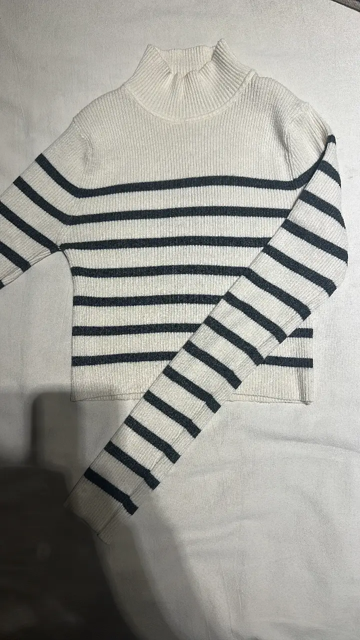 Sweater de cuello alto a rayas horizontales en blanco y negro, ideal para un look casual y abrigado. Perfecto para combinar con jeans o pantalones de vestir.
