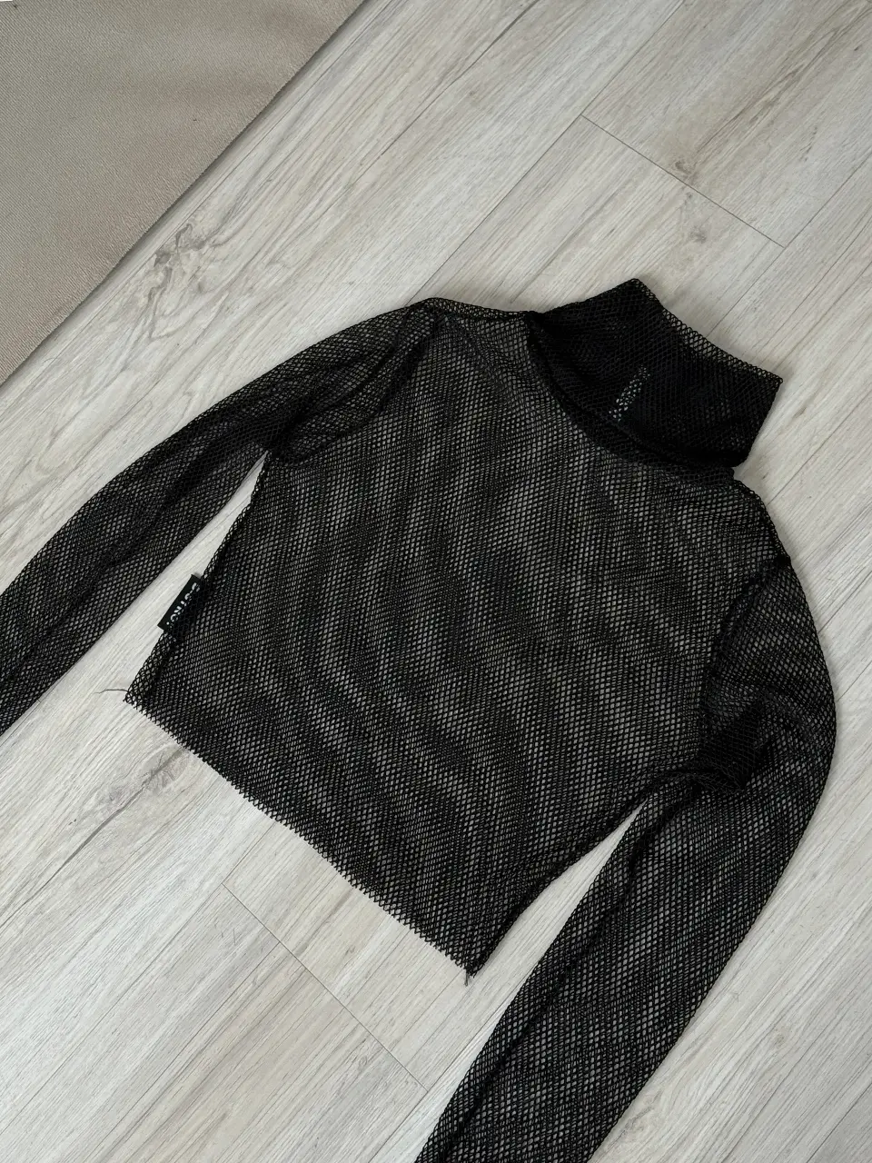 Remera de manga larga de red, con cuello alto. Ideal para looks audaces y modernos.