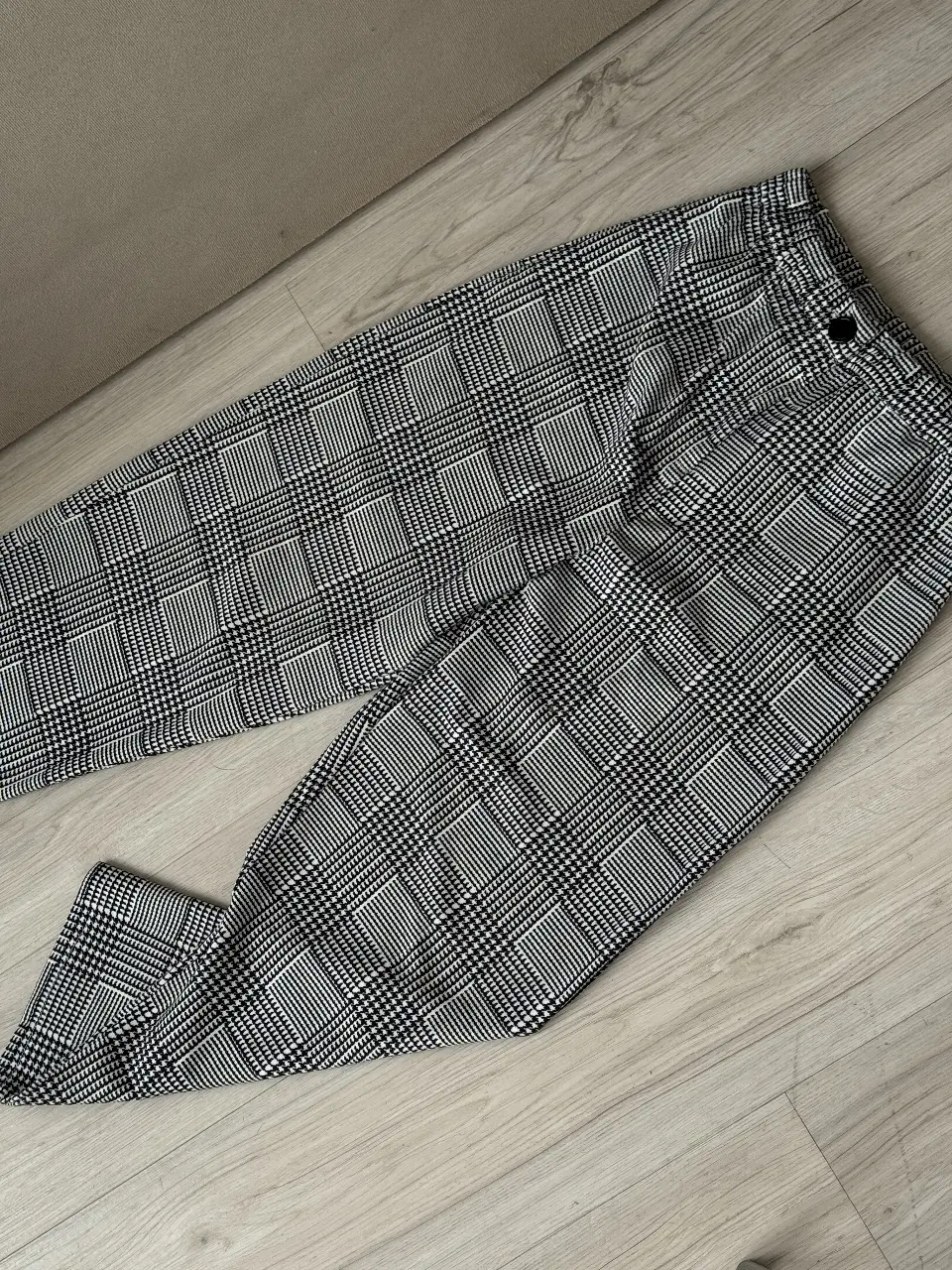 Pantalón sastrero de mujer con estampado a cuadros en blanco y negro. Corte recto y tiro medio. Ideal para un look elegante y moderno.