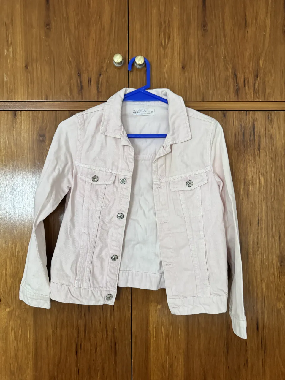 Campera de jean rosa, con botones metálicos y cuello clásico. Tiene bolsillos en el frente.