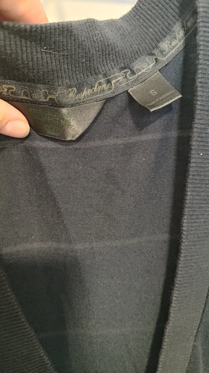 vestido negro sin mangas con escote en V y un detalle de corona dorada en el pecho. Ideal para un look casual o de salida.