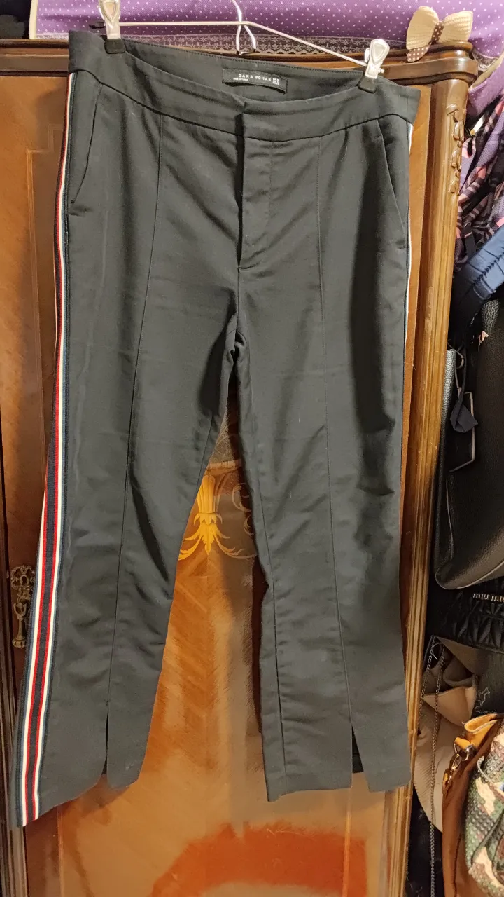 Pantalón negro de vestir con detalles de tiras laterales en rojo, blanco y azul. Posee tajos en los bajos y un corte recto. elastizado 