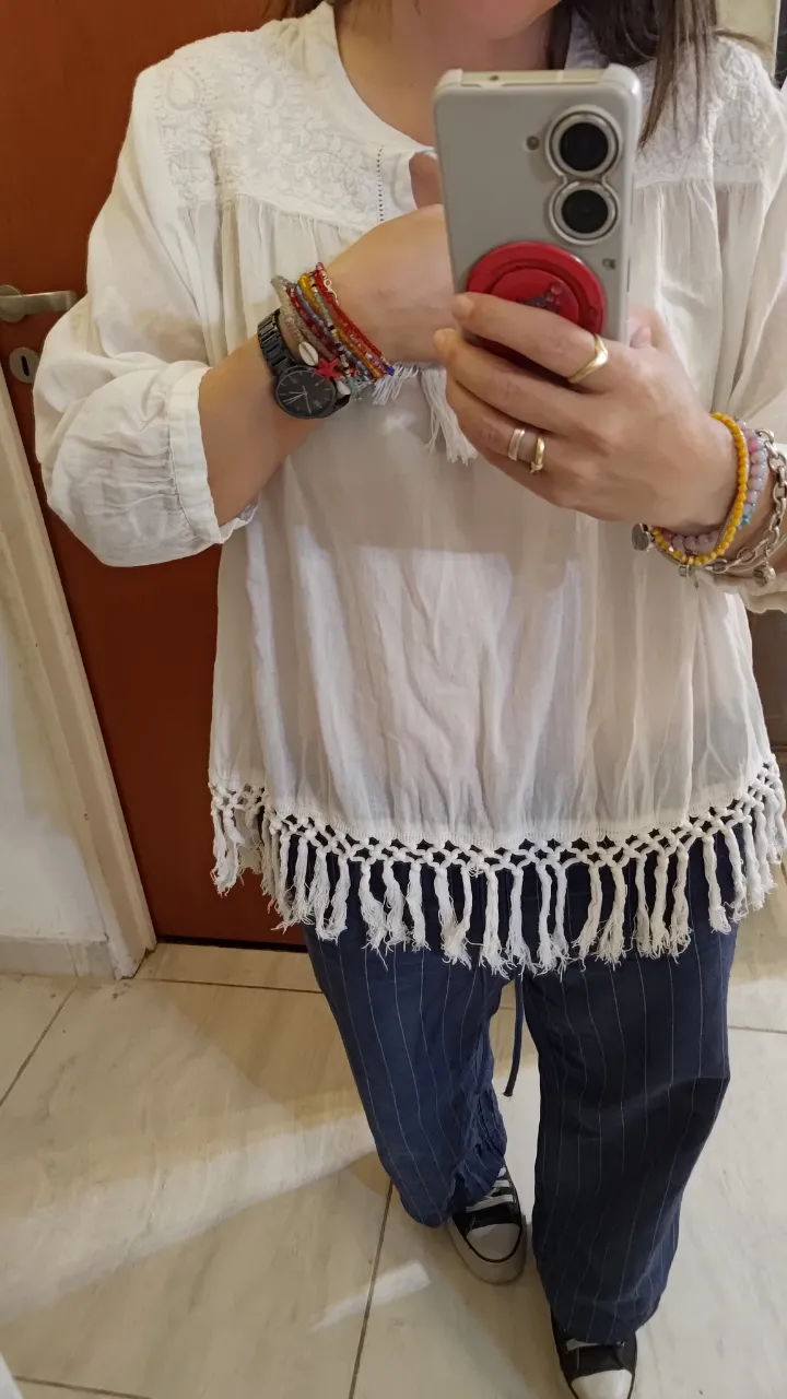 Blusa blanca de algodón con bordados y detalles de macramé en el escote y en el ruedo. Mangas largas con puño. Estilo boho chic, ideal para un look relajado y femenino.