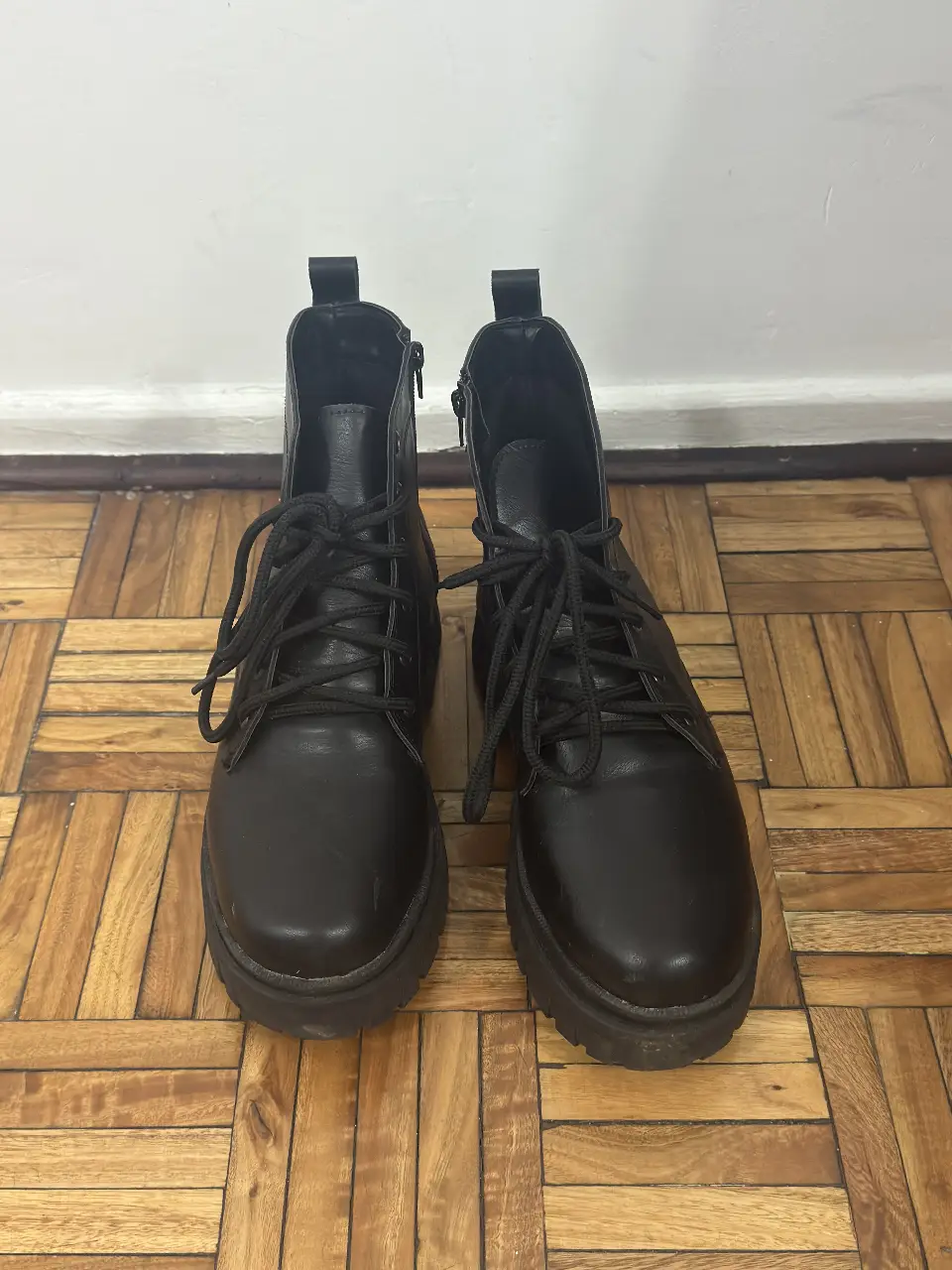 Botines negros de cuero sintético con cordones y cierre lateral. Suela gruesa y diseño moderno, ideales para un look urbano y versátil.