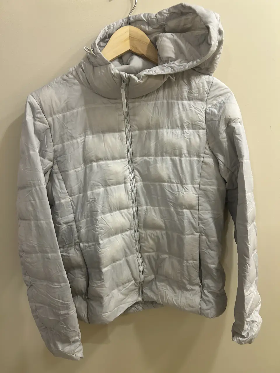 Campera de pluma Uniqlo, color gris claro, con capucha, cierre frontal y bolsillos. Ideal para el invierno.