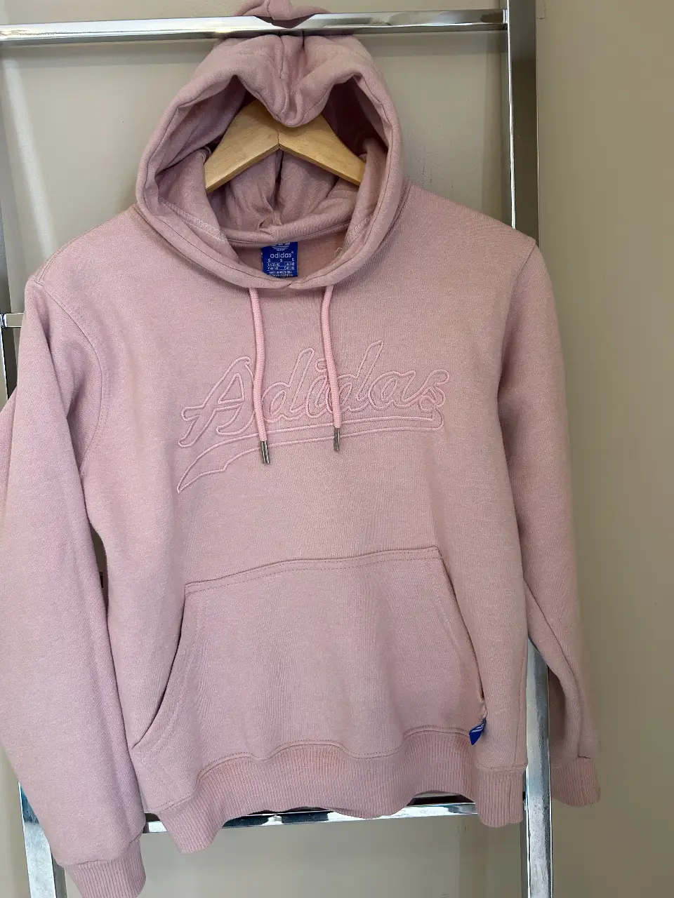 Buzo canguro Adidas rosa, con capucha y bolsillo frontal. Logo Adidas bordado en el pecho. Talle S.