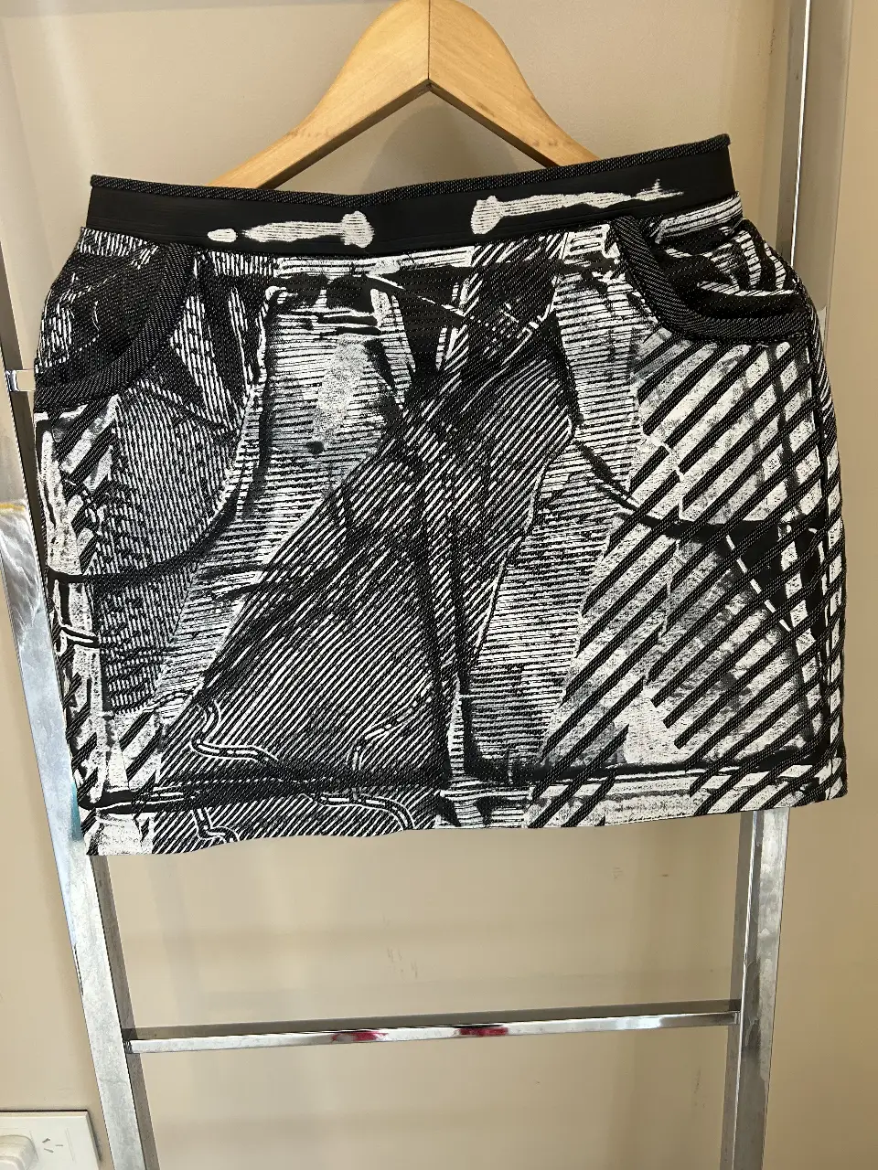 Minifalda con estampado abstracto en blanco y negro. Diseño con bolsillos y cierre trasero engomada Ideal para un look moderno y versátil.