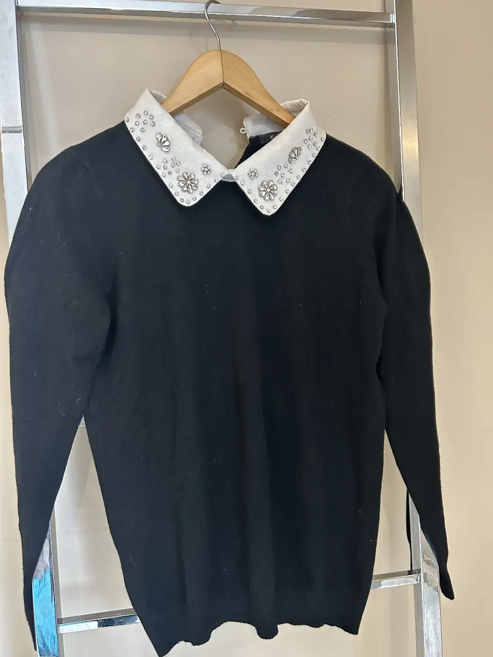Sweater negro con cuello blanco adornado con detalles brillantes. Un diseño elegante y sofisticado para cualquier ocasión.