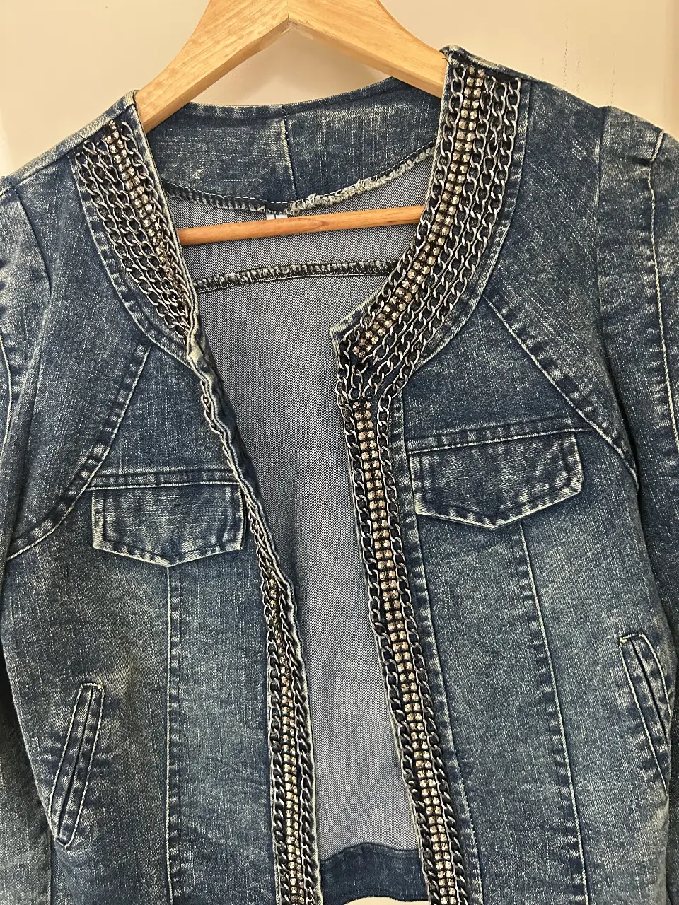 Campera de jean azul con detalles de cadenas plateadas y brillos en el cuello . Un diseño único y moderno para un look audaz.elastizada