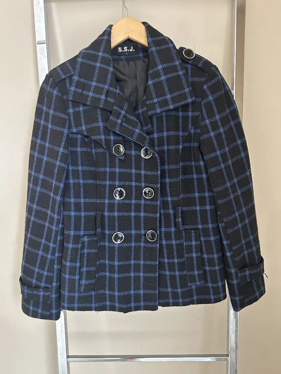 Tapado de paño para mujer, con diseño a cuadros en negro y azul. Posee botones y bolsillos. Ideal para el invierno.