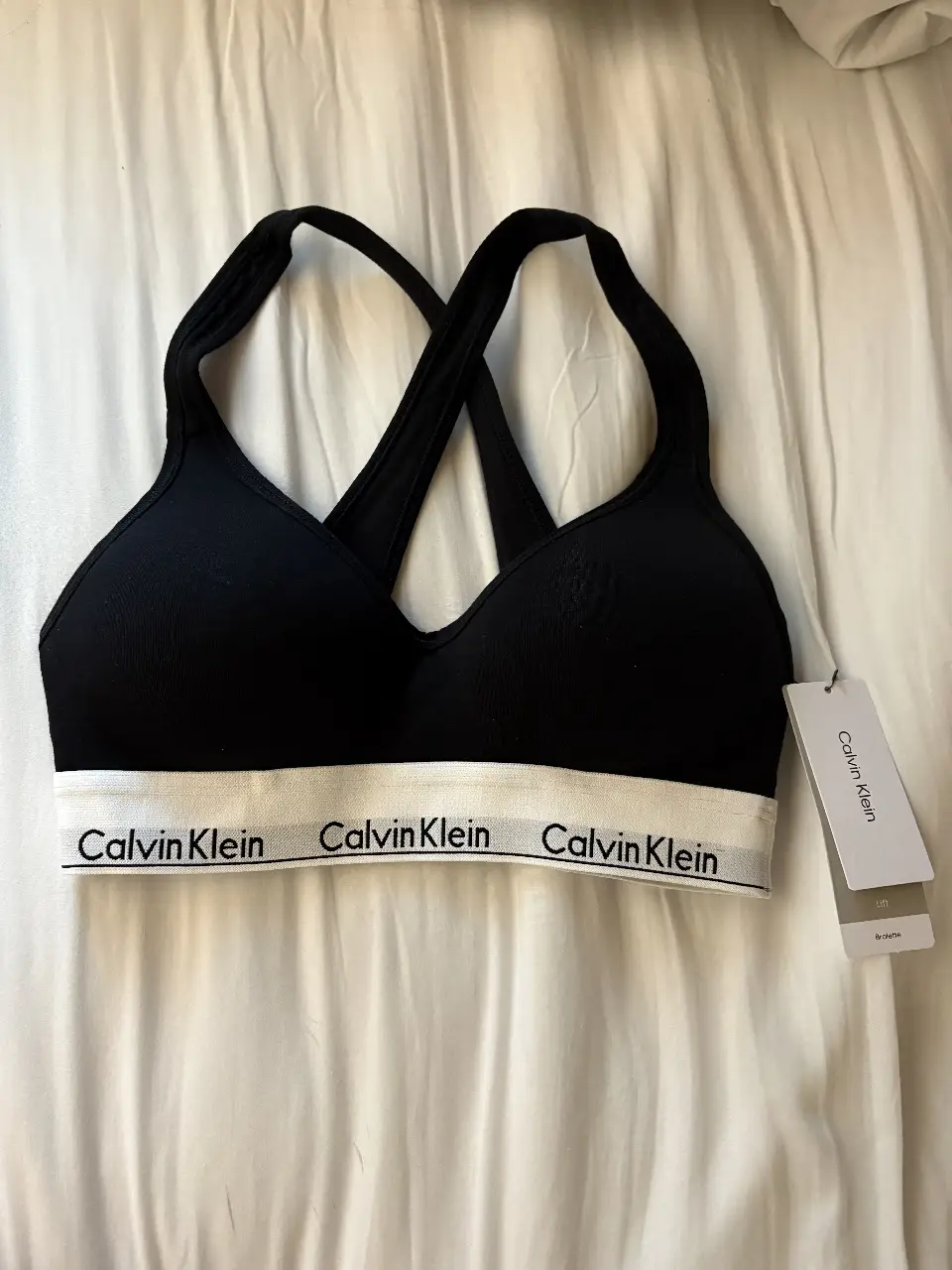 Corpiño deportivo Calvin Klein en color negro con detalles en blanco. Ideal para actividades de bajo impacto, con el logo de la marca en la banda inferior. Cómodo y con estilo.