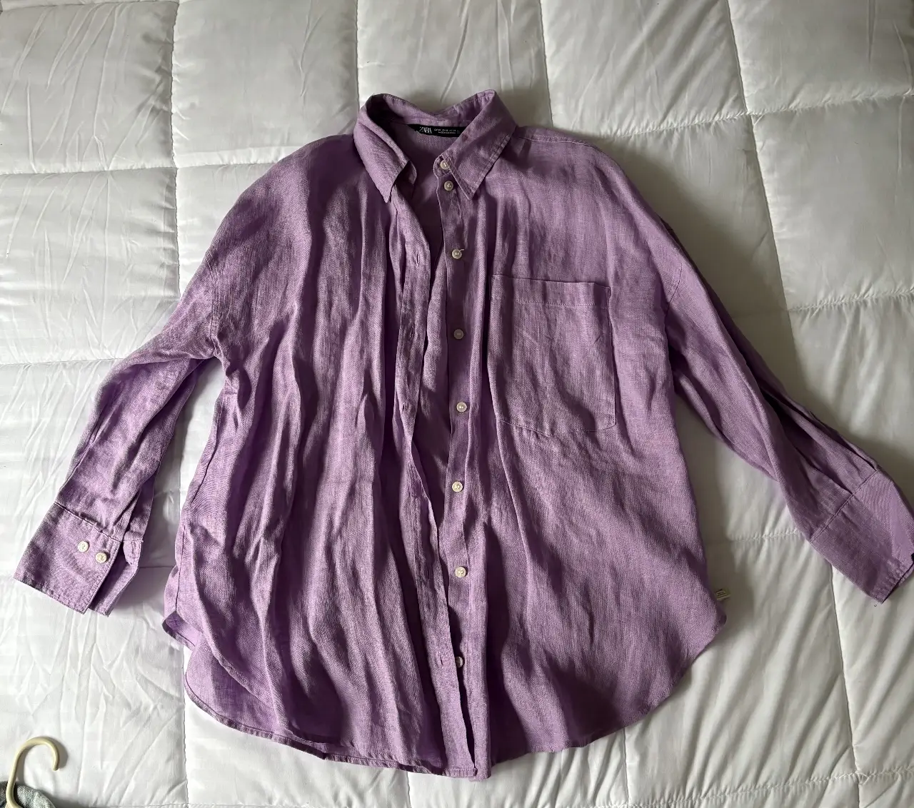 Camisa de lino violeta de la marca Zara, con un bolsillo en el pecho y botones. Ideal para un look casual y fresco.