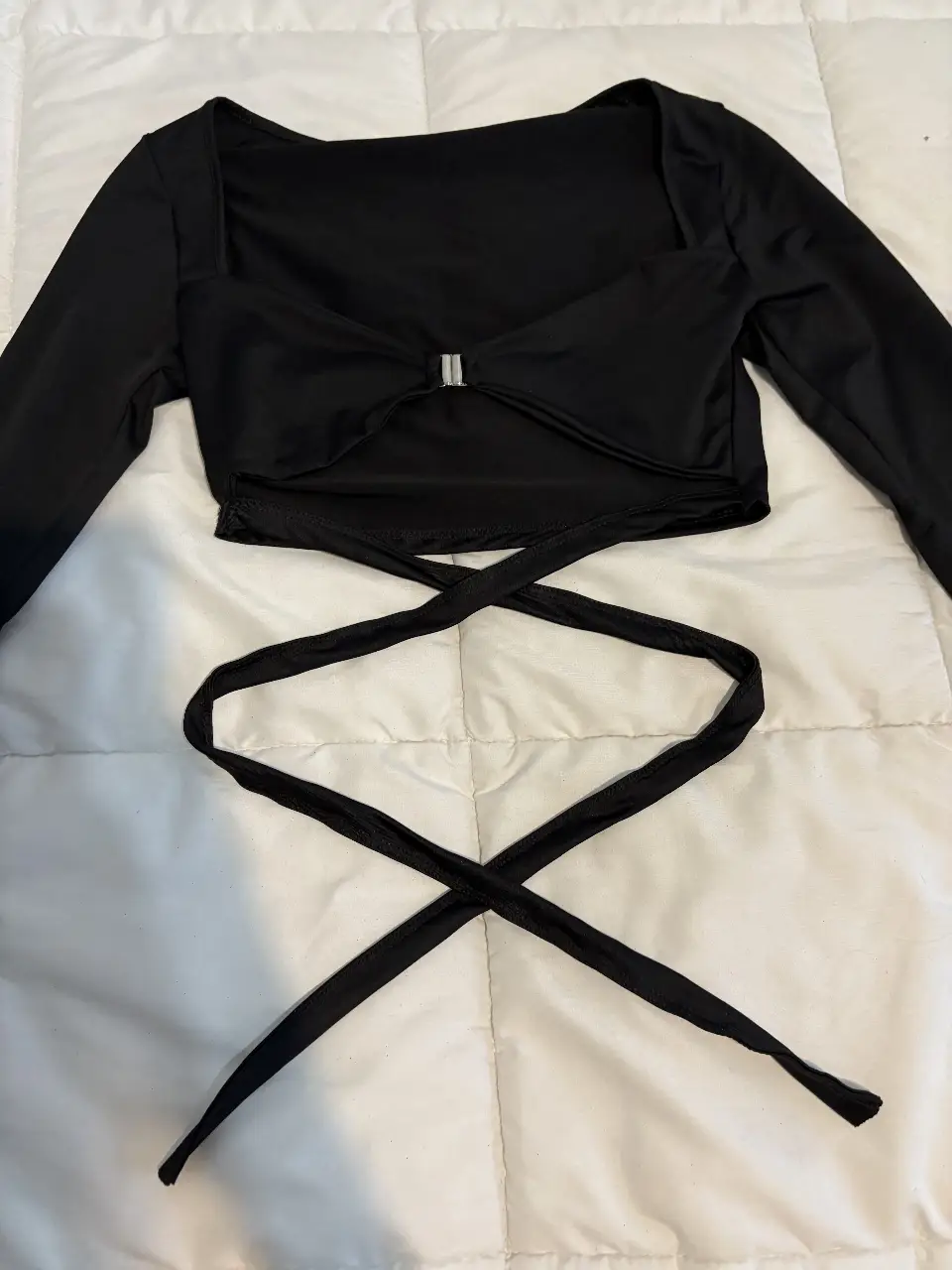 Top negro con mangas largas y escote cuadrado. Diseño con detalle de lazo en el frente y tiras para atar en la cintura. Ideal para un look moderno y sofisticado. NO ES DE MARCA!