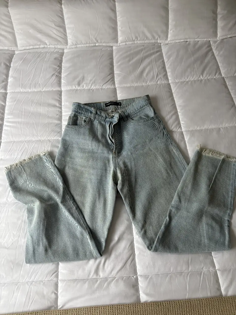 Jeans rectos de mujer, tiro medio, con un diseño rayado en color azul claro. El corte es recto con un ligero desflecado en los bajos, ideal para un look casual y moderno.