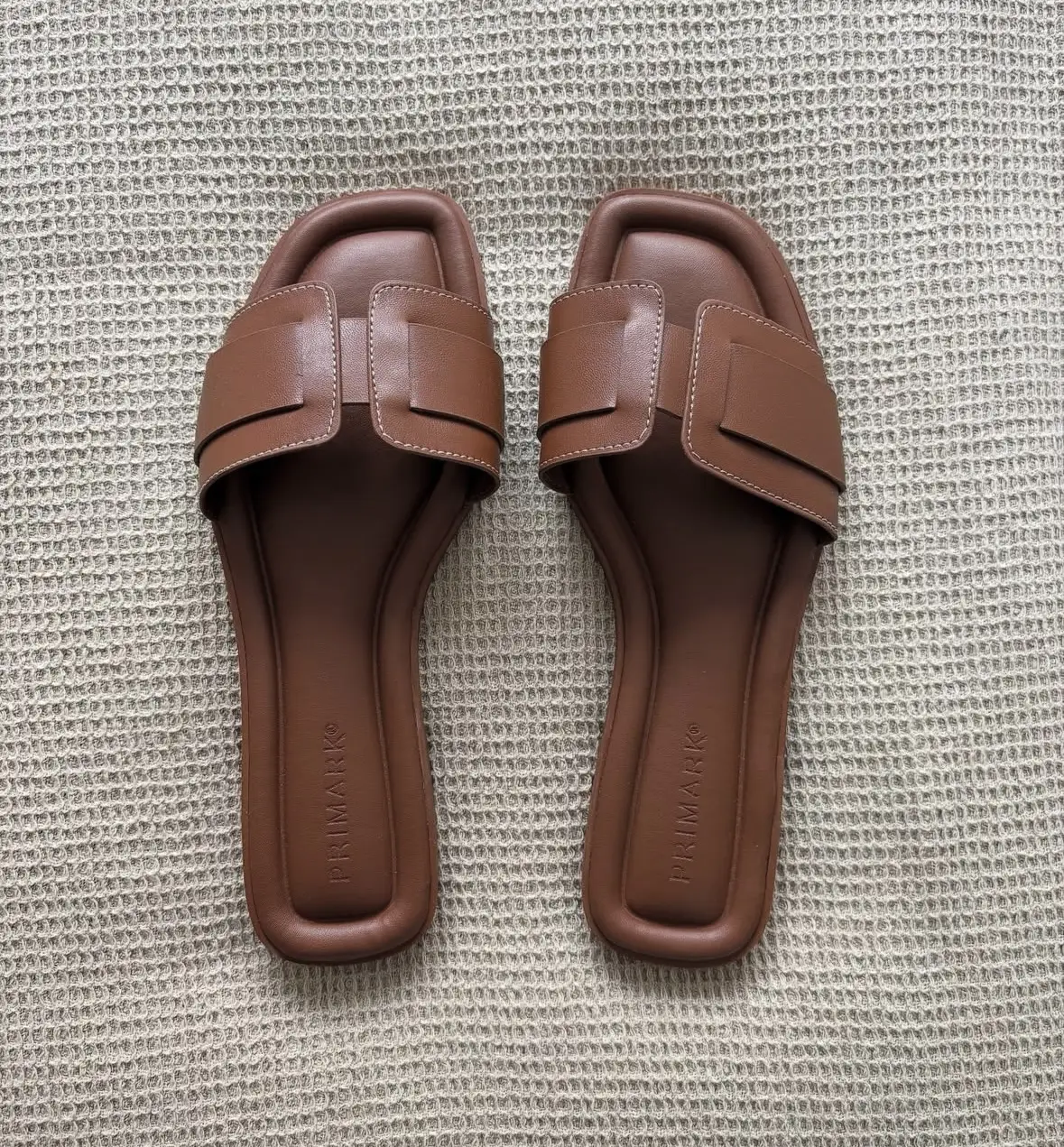 Sandalias planas de mujer, color marrón, con diseño moderno y elegante. Ideales para el verano, cómodas y versátiles para combinar con diferentes outfits.