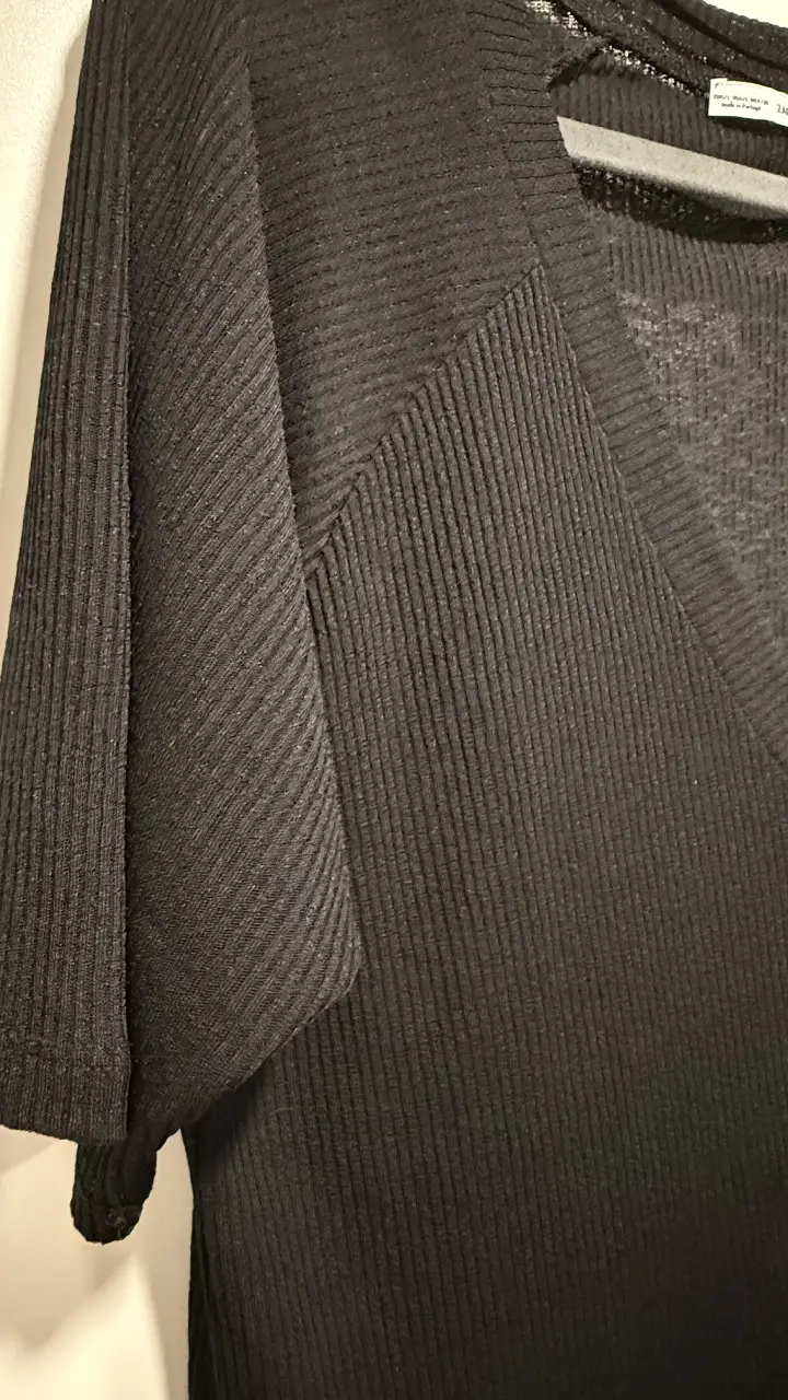 Blusa negra de Zara, con cuello en V y mangas cortas. Ideal para un look elegante y versátil.
