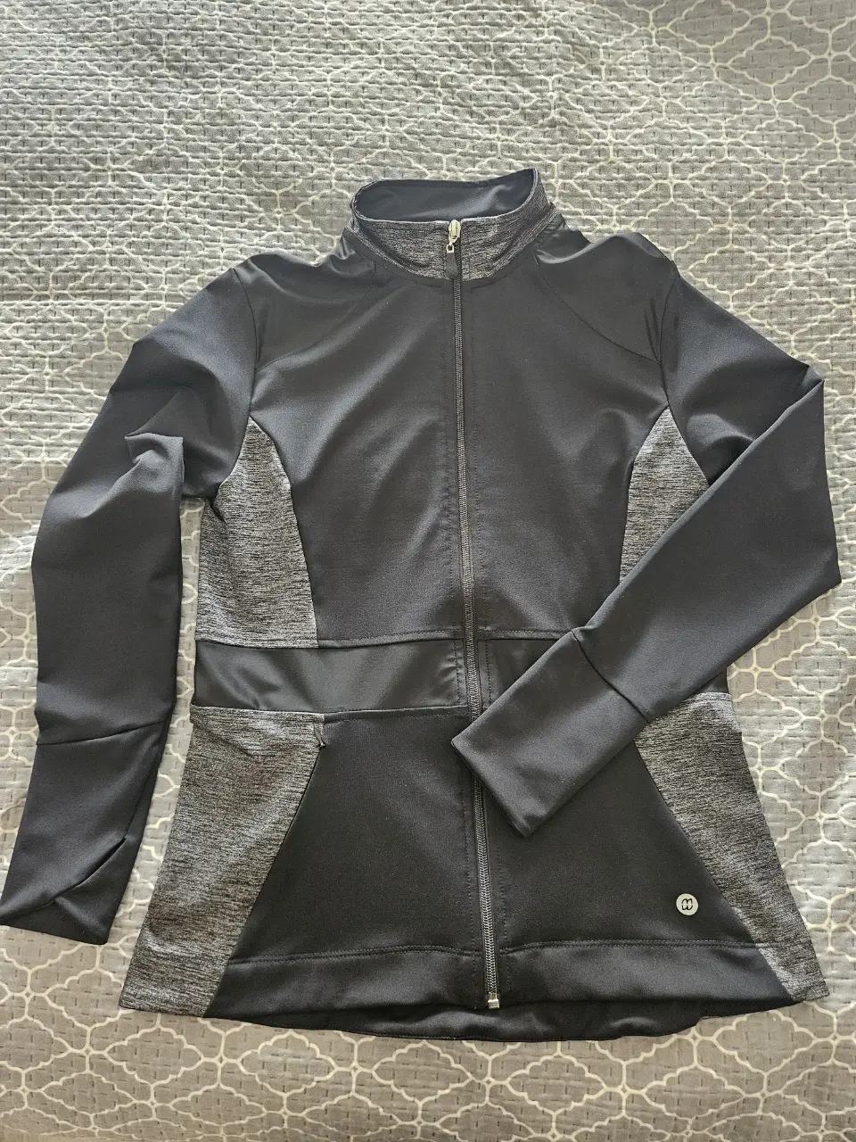 Campera deportiva de mujer marca MIWOK LA PLATA, entallada modela la figura, color negro con detalles en gris. Con cierre frontal, cuello alto, puño con espacio para pulgares y bolsillos con cierre invisible. Ideal para actividades físicas, como nueva.