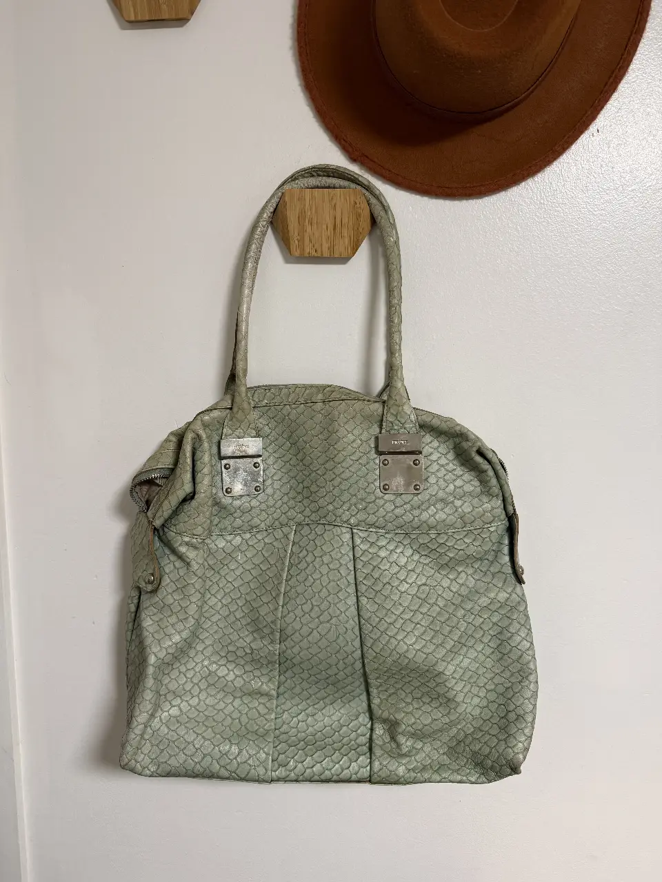 Cartera de mano de cuero con diseño de escamas en tono verde agua. Detalles metálicos plateados.  super práctica, la verdad la usé un montón, tiene detalles del uso, y unas marchitas de pintura que muestro en la foto, por eso su valor tan bajo 