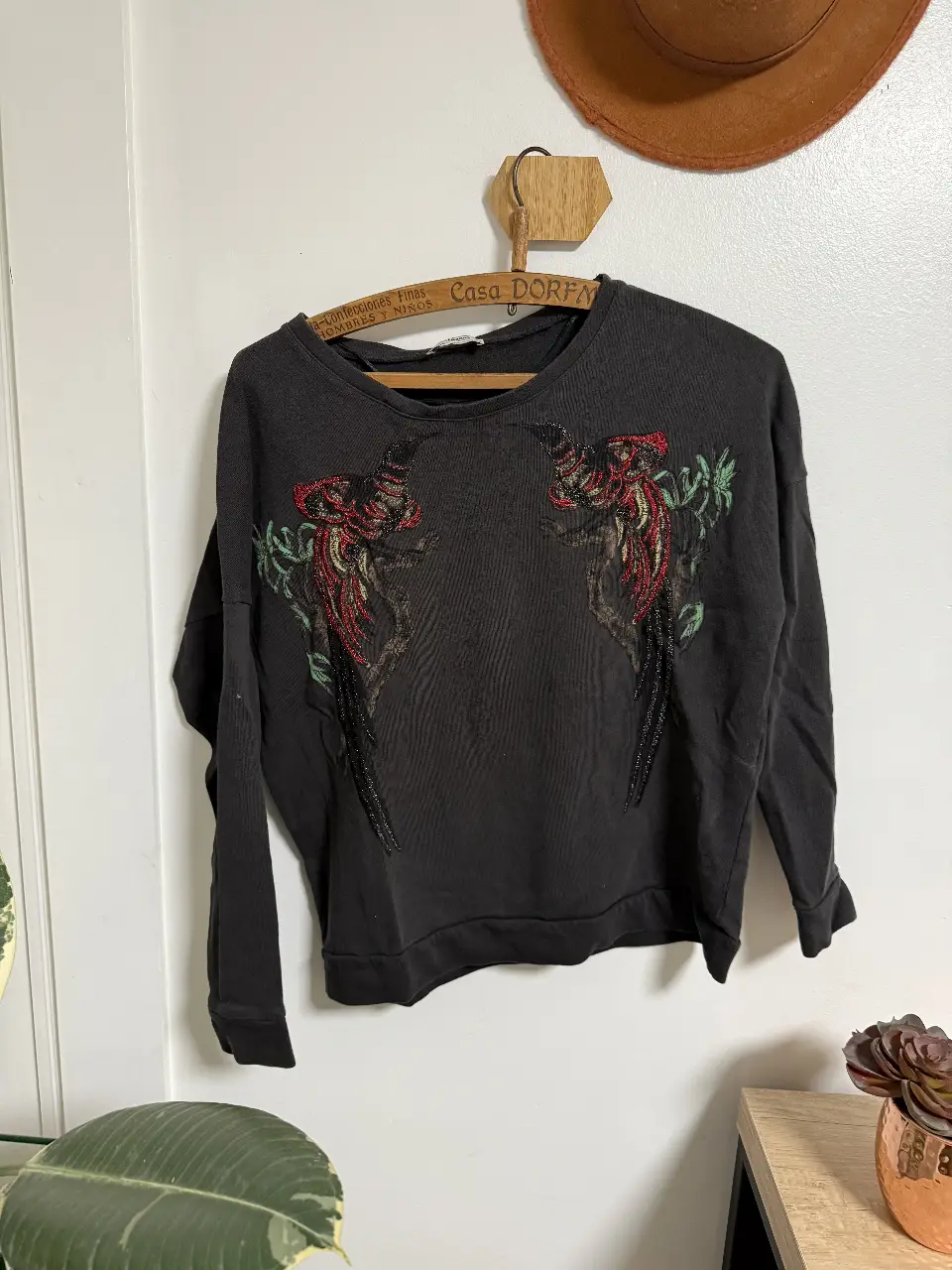Buzo de cuello redondo negro con bordado de diseño floral en la parte delantera. Ideal para un look casual y cómodo. talle 28 mex