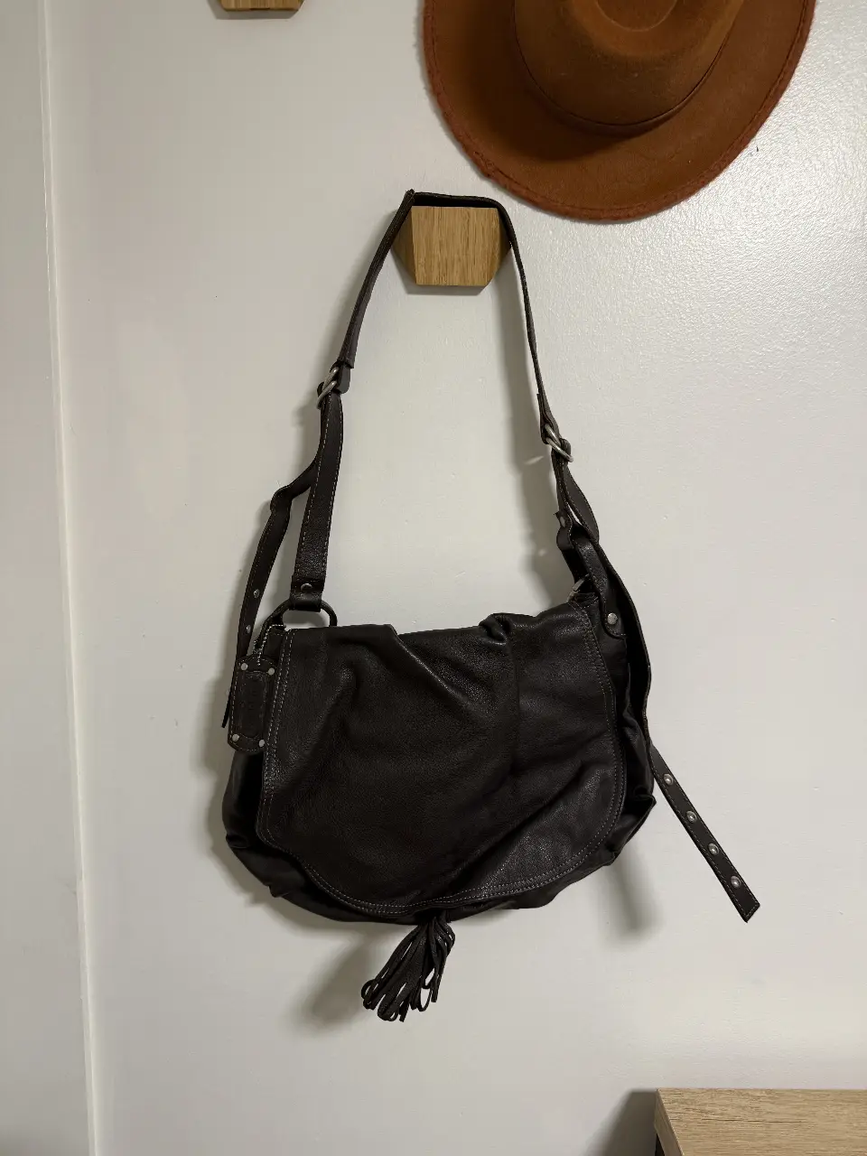 Cartera bandolera de cuero marrón oscuro, con diseño de solapa y detalle de flecos. Ideal para un look casual y versátil. color chocolate. marca cul de sac , interior forrado con bolsillos 