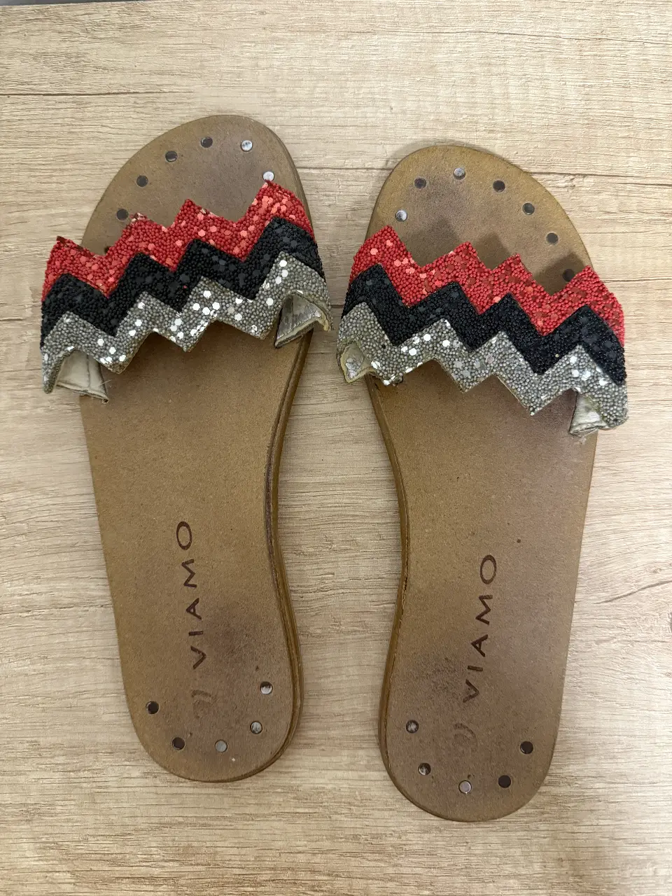 Sandalias planas de mujer con diseño zig-zag en la capellada. Detalles de lentejuelas y base marrón.