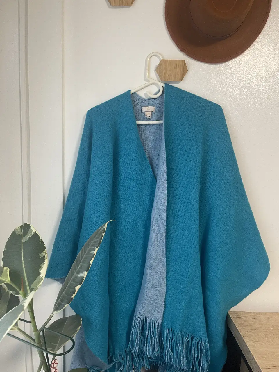 Poncho reversible de color azul turquesa y celeste claro, con flecos en el borde inferior. Ideal para un look casual y abrigado para esta temporada de frio