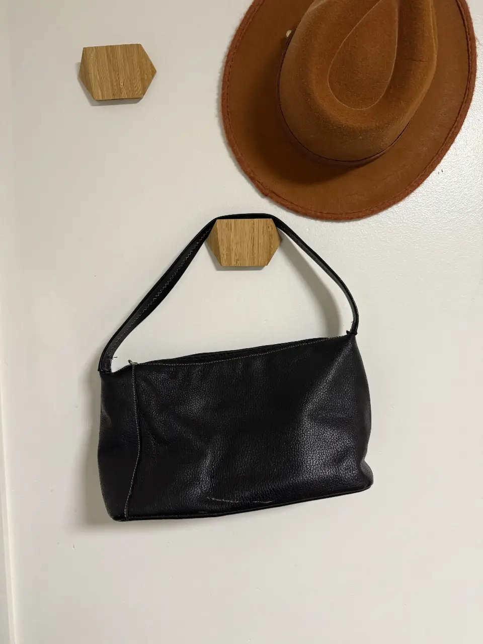 Cartera negra de cuero, estilo baguette, con detalles de costura en blanco. Ideal para un look casual y elegante. Prüne. en el frene, tiene una marca dorada, nose su origen. no es rayón. 