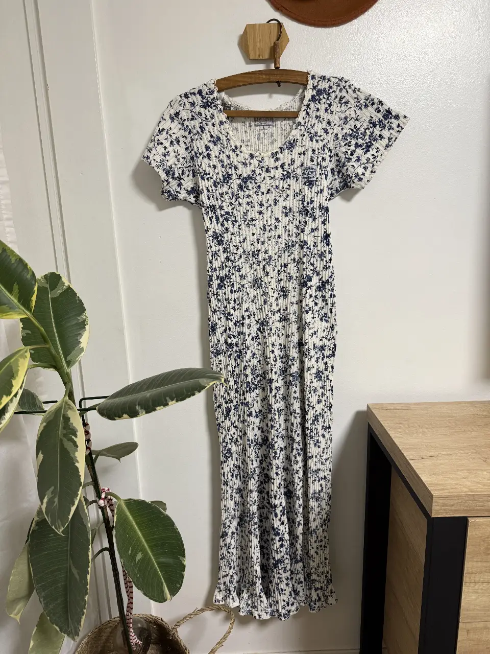 Vestido midi de tejido plisado con estampado floral en blanco y azul. Tiene mangas cortas y un detalle de ajuste en la espalda. marca new derway 